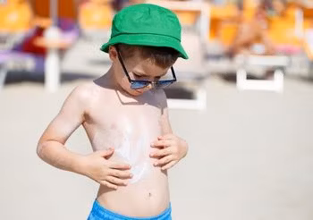 Chłopiec smaruje się kremem